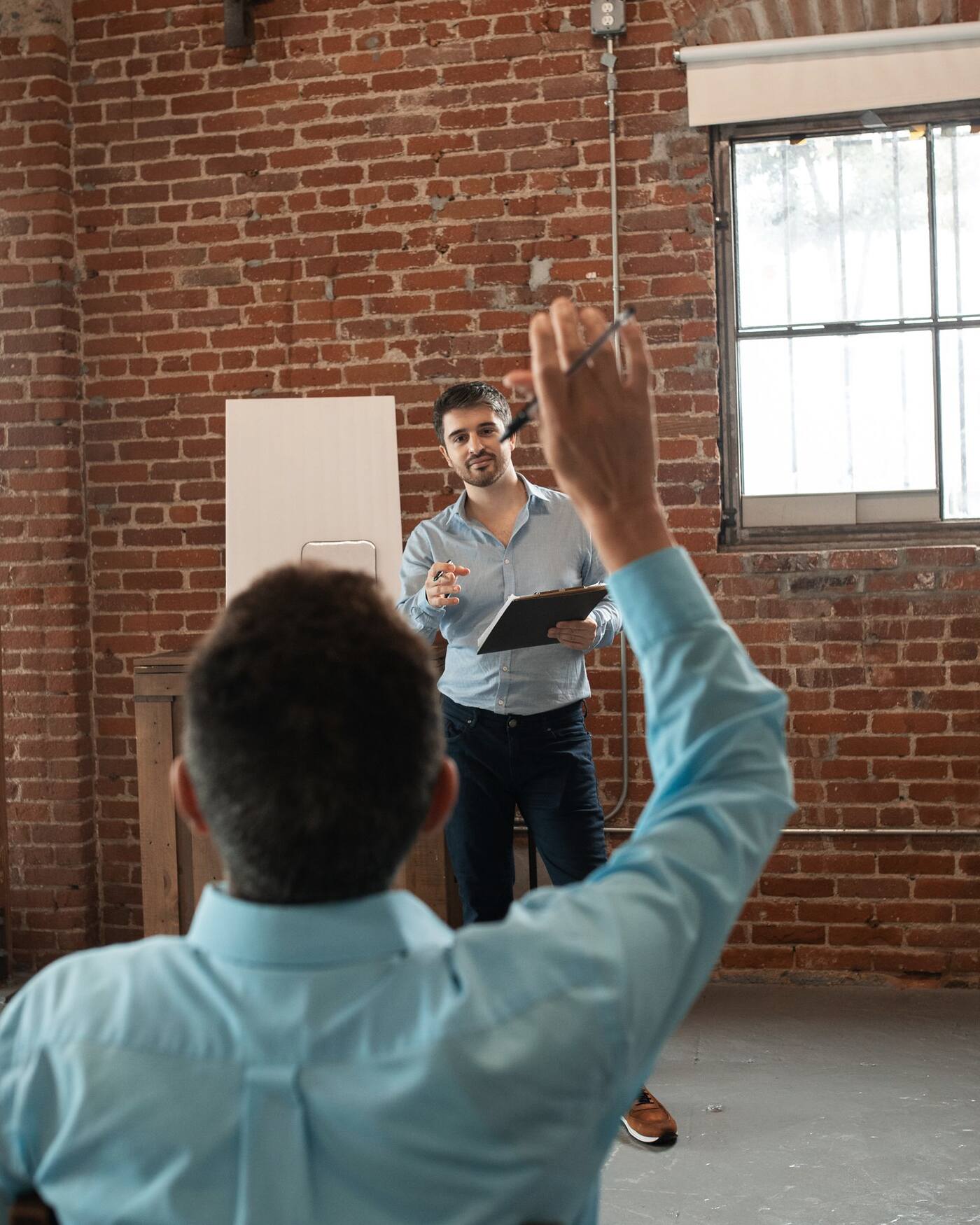 Un participant lève la main pendant une session de formation, le formateur lui répond