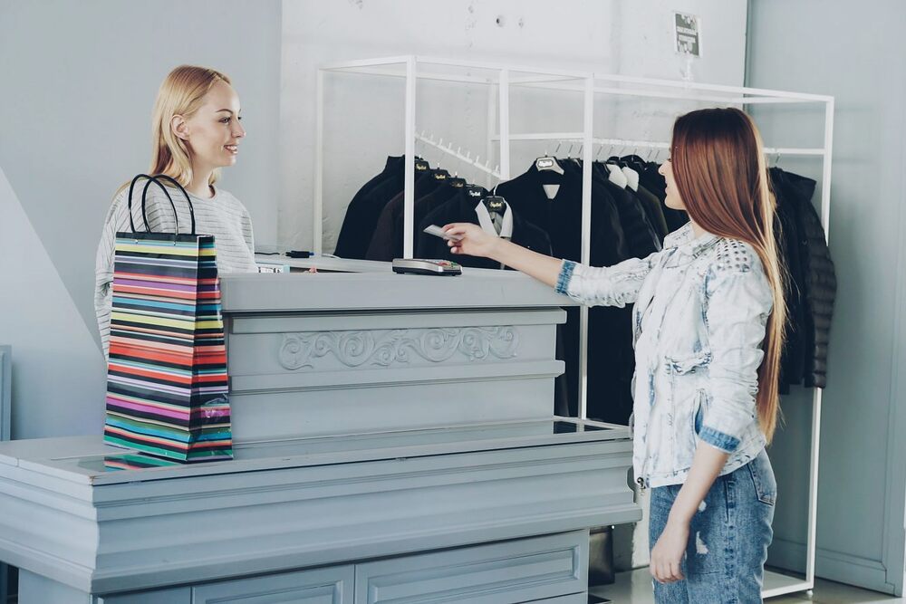 Vendeuse encaissant une cliente au comptoir d'une boutique