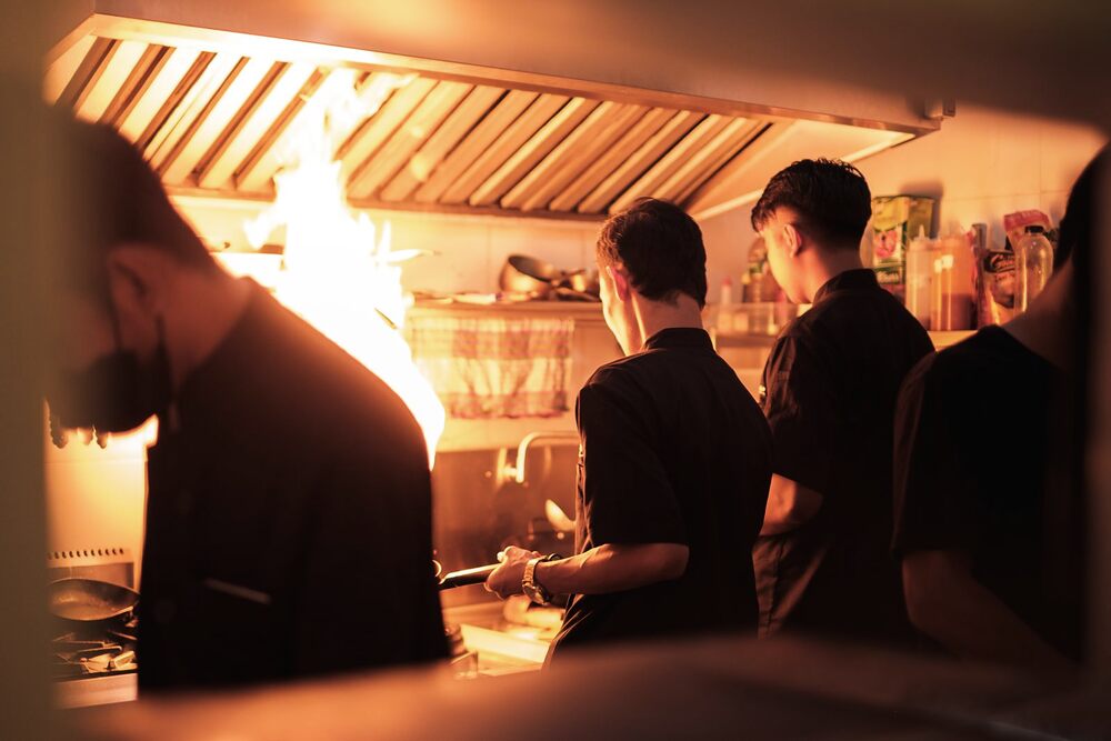 Cuisiniers au travail derrière le piano d'une cuisine professionnelle