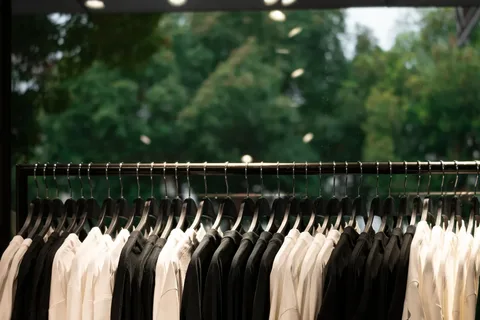 Portant de chemises noires et blanches sur cintres dans une boutique de prêt-à-porter