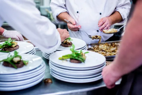 Cuisiniers dressant des assiettes au passe d'une cuisine de restaurant