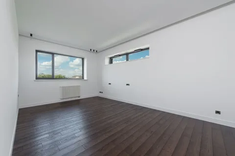 Pièce vide d’un logement, parquet foncé et fenêtres donnant sur le ciel