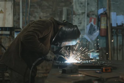 Soudeur à l'arc masque baissé sur un établi d'atelier de métallerie