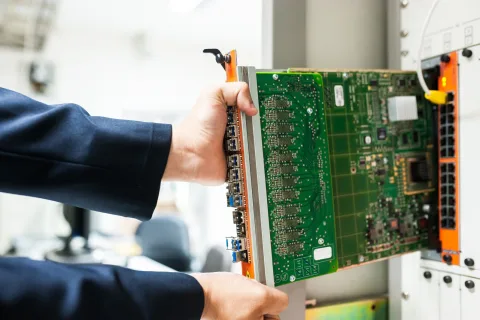 Technicien insérant une carte réseau à fibres optiques dans une baie