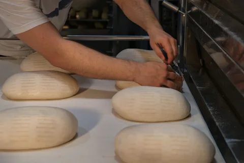 Boulanger lamant des pâtons au coupe-pâte avant l'enfournement
