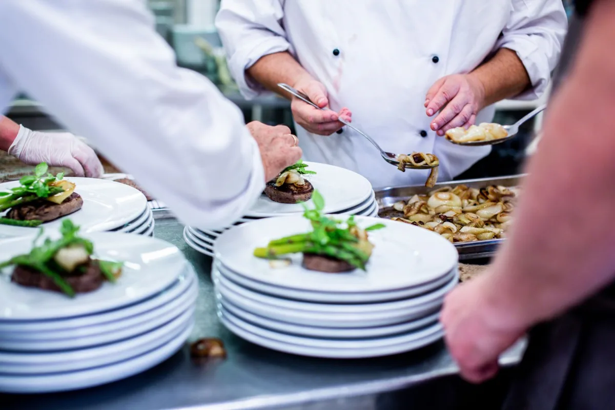 Cuisiniers dressant des assiettes au passe d'une cuisine de restaurant
