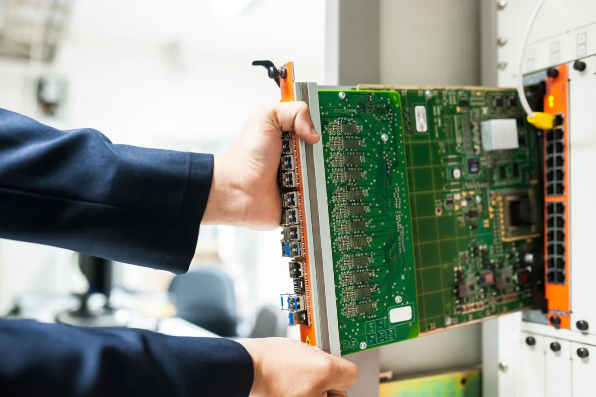 Technicien insérant une carte réseau à fibres optiques dans une baie